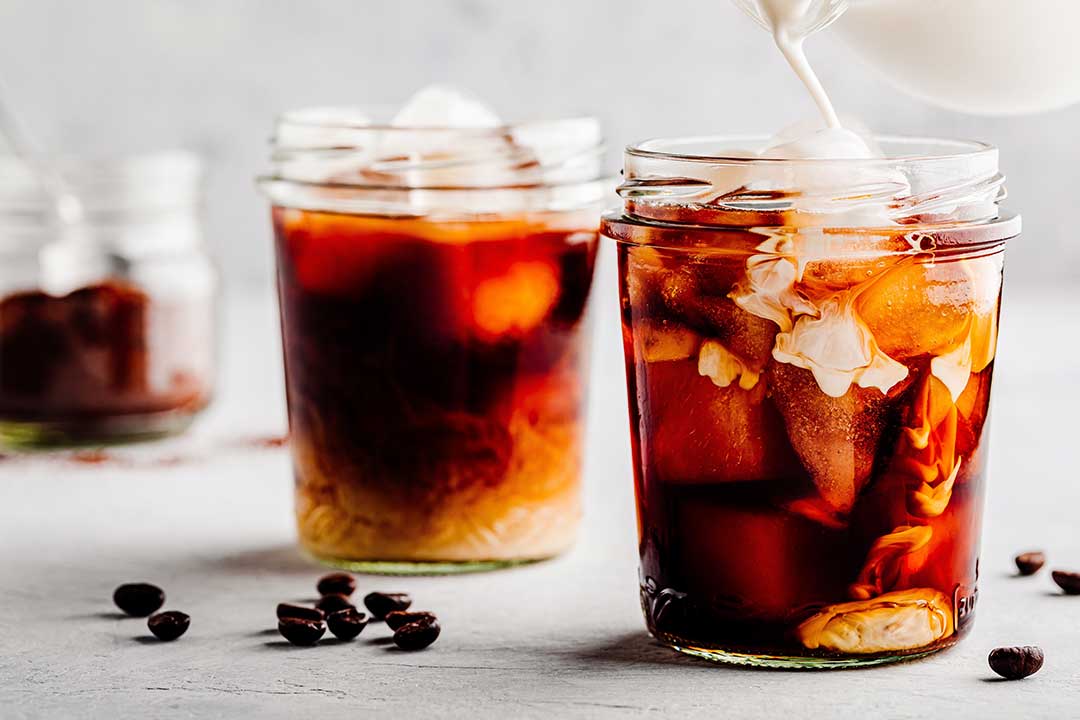 How to Cold Brew Tea—Image shows glasses of milk tea on a white, wooden surface