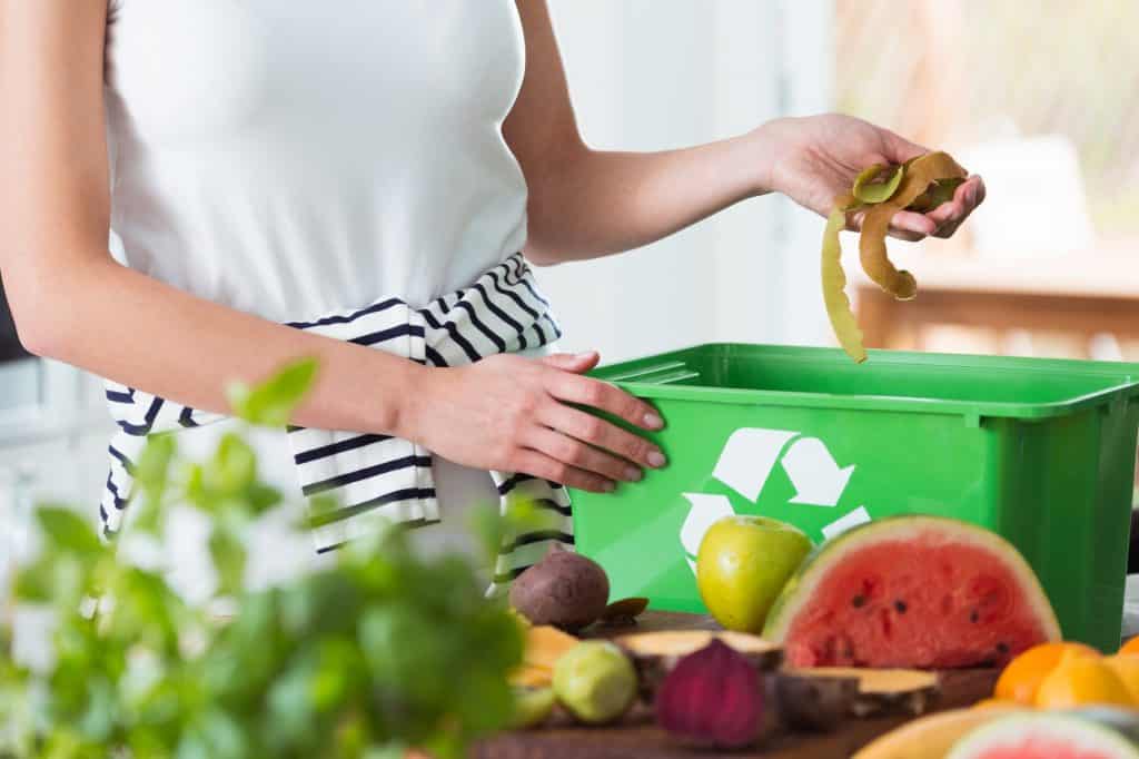 Composting is a great way to reduce waste and improve your garden. Learn more about the benefits of composting and how to get started today! (Pictured: Woman composting organic kitchen waste)