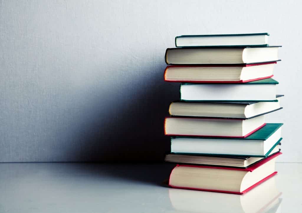 Rock collecting is one of a few hobbies that has the potential to be both rewarding and profitable. Learn more in our rock collecting for beginners guide!  (Image shows stack of red, green and black books on white reflective surface)