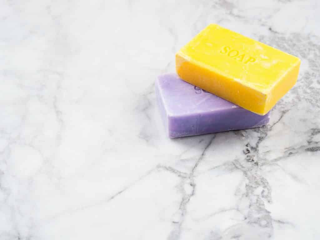 Looking for the best melt and pour soap base to supplement products or to give as gifts for friends and family? Check out some of our favorites! (Image shows lemon and lavender artisanal soap bars on marble background)