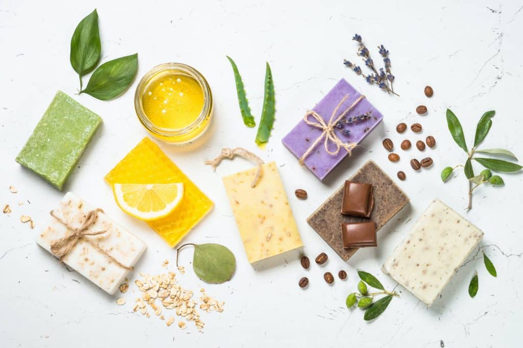 Looking for the best melt and pour soap base to supplement products or to give as gifts for friends and family? Check out some of our favorites! (Image shows assorted natural soap bars on a white  background, top view)