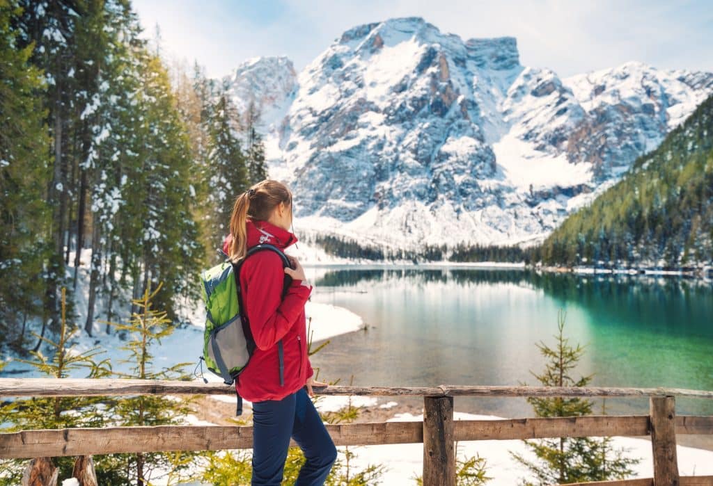 Young woman with backpack near wooden fence and Braies lake