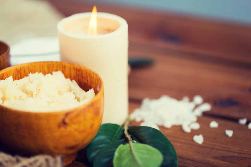 close up of natural body scrub and candle on wood