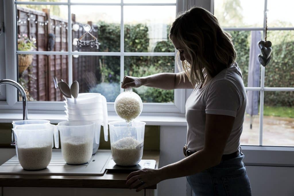 Woman standing in a domestic kitchen, making jar candles.