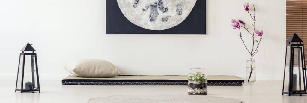 Moon poster above futon in Japanese bedroom interior with flower