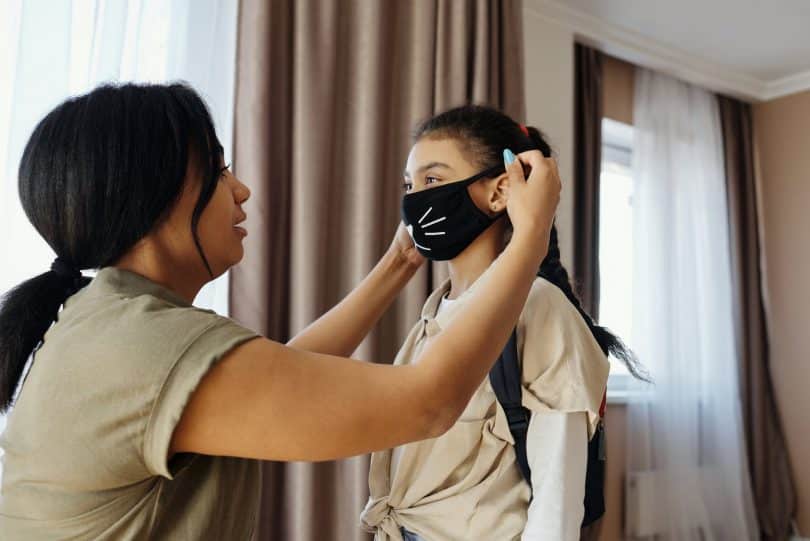 mother putting a face mask on her daughter