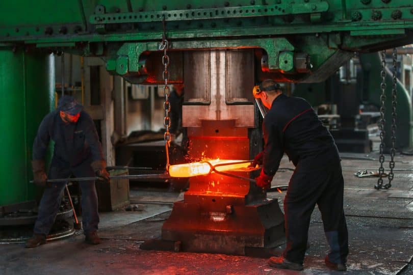 two men holding two gray metal tools