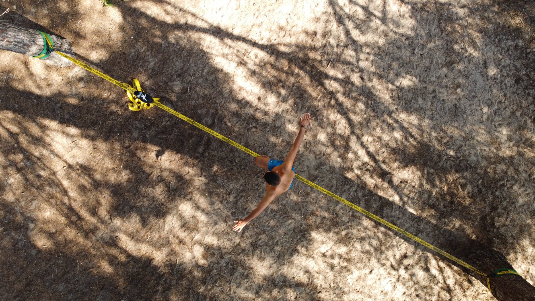 shirtless man waking on a yellow rope