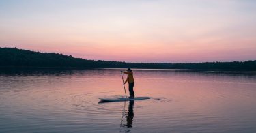 man riding board on middle of body of water