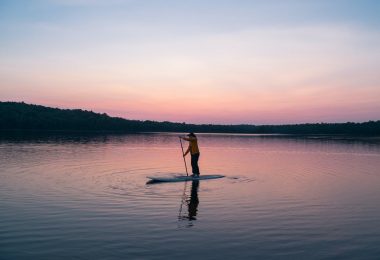 man riding board on middle of body of water
