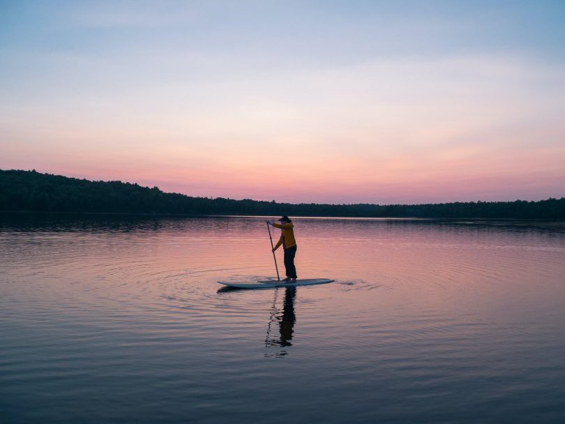 man riding board on middle of body of water