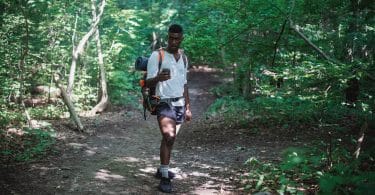 african american man with backpack in forest