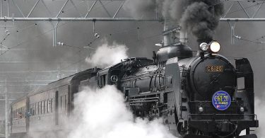 black train on rail and showing smoke