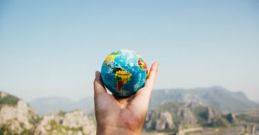 person holding world globe facing mountain